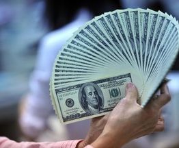 A clerk counts US dollar bills at a bank