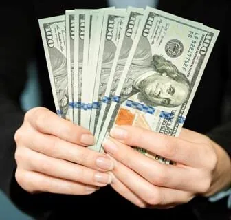 Person holding hundred dollar bills