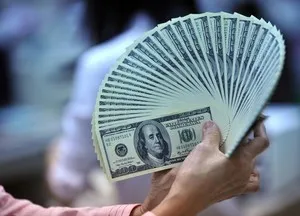 Person holding fan of 100 dollar bills