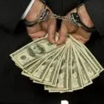 image of man in handcuffs holding money behind back